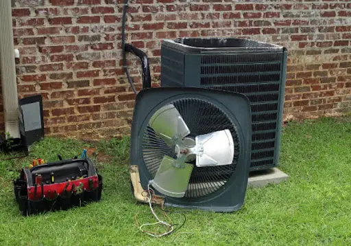 A condenser fan assembly removed for repair, set out on the grass